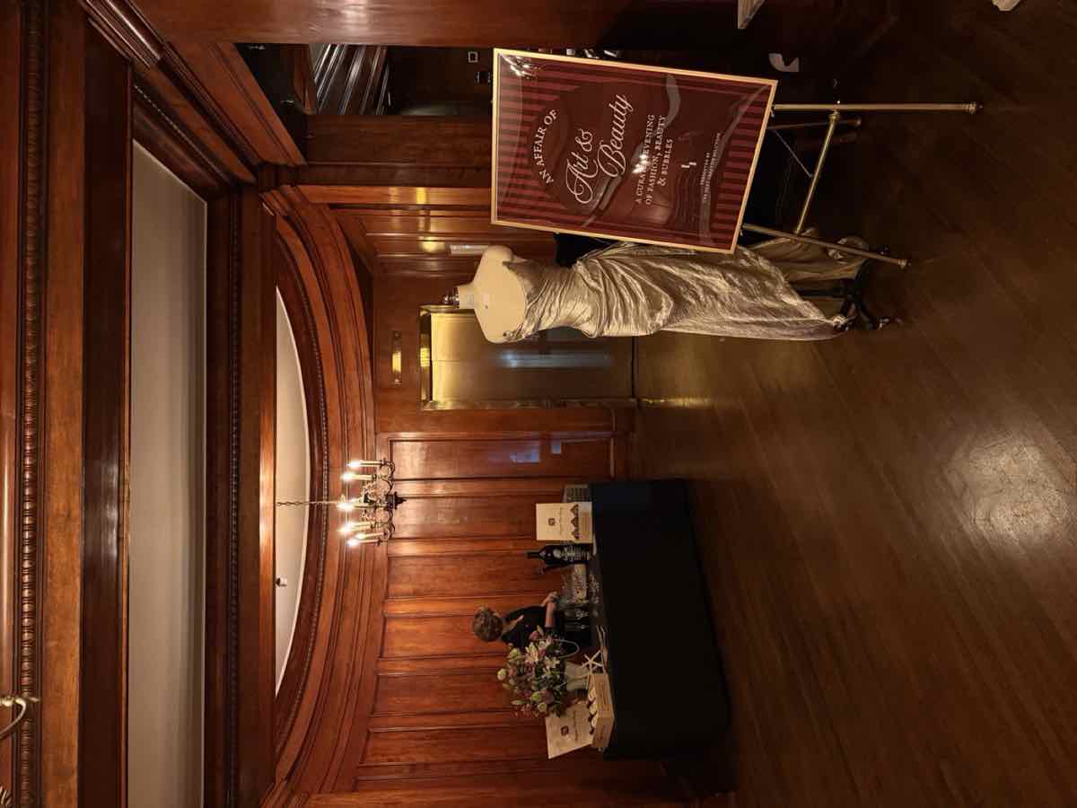 The entrance to An Affair of Art & Beauty at Hotel Sorrento, with a gown on display and the event sign