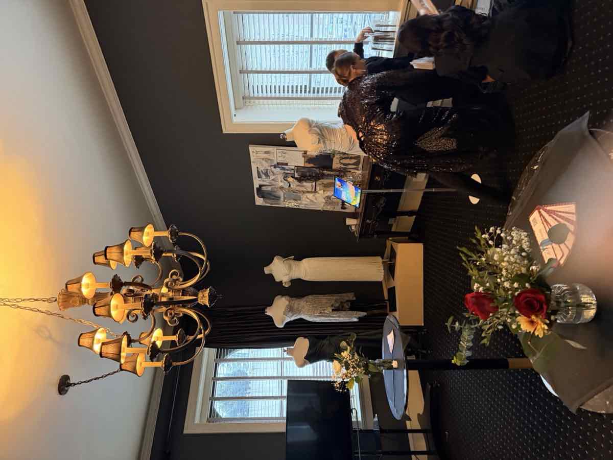 Gowns on display in a room with a chandelier