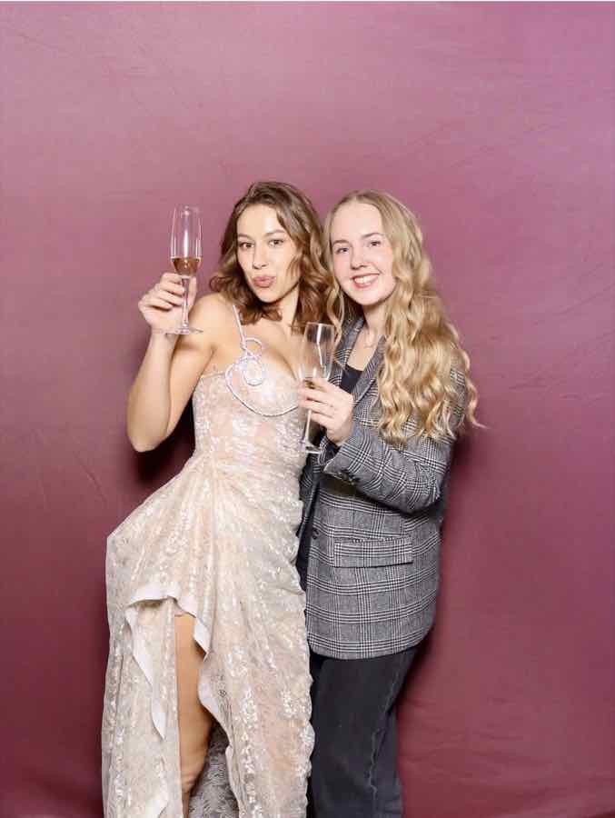 Taylor and a friend raising champagne glasses at the photo booth