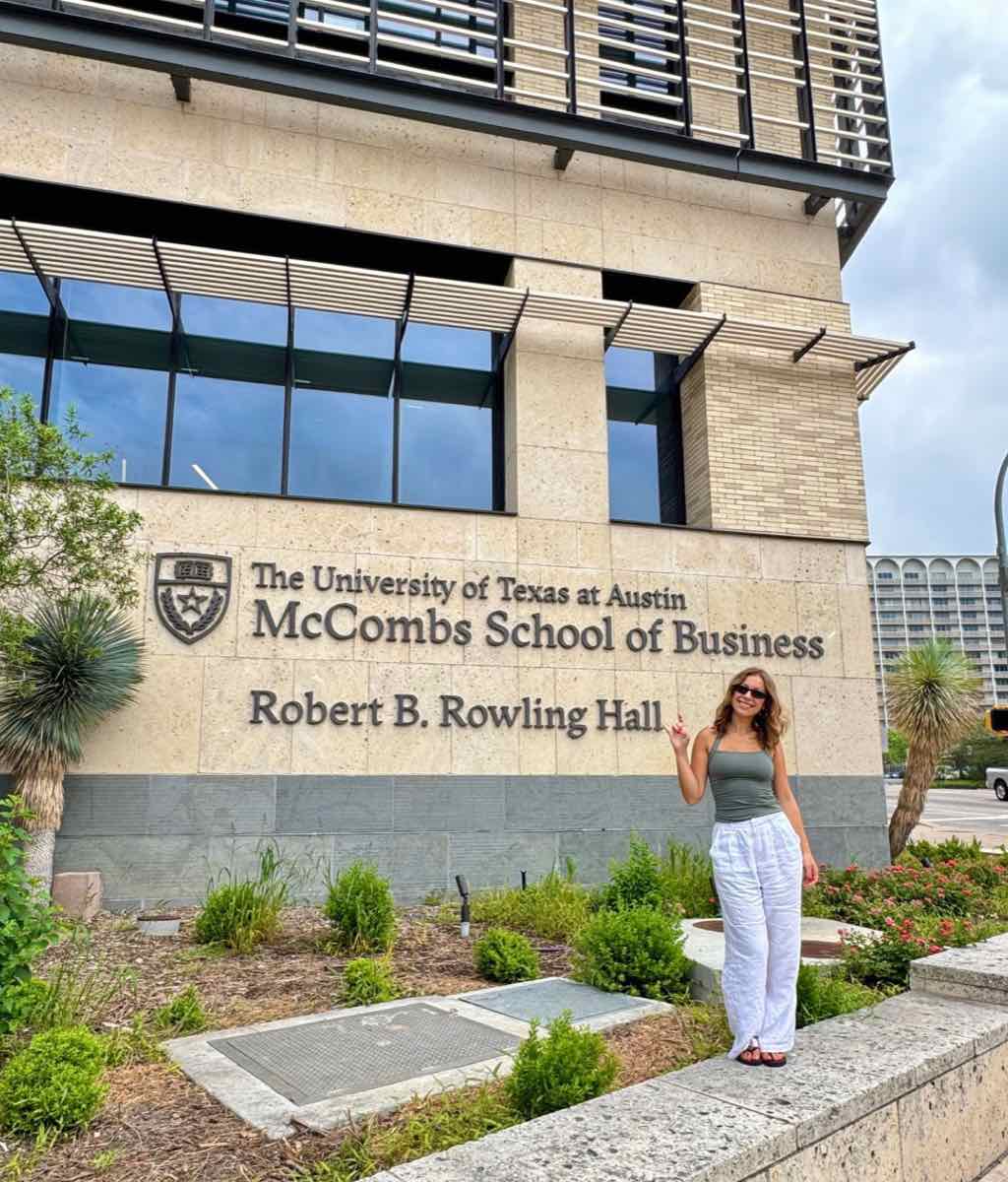 Taylor pointing to the McCombs School of Business sign on Robert B. Rowling Hall