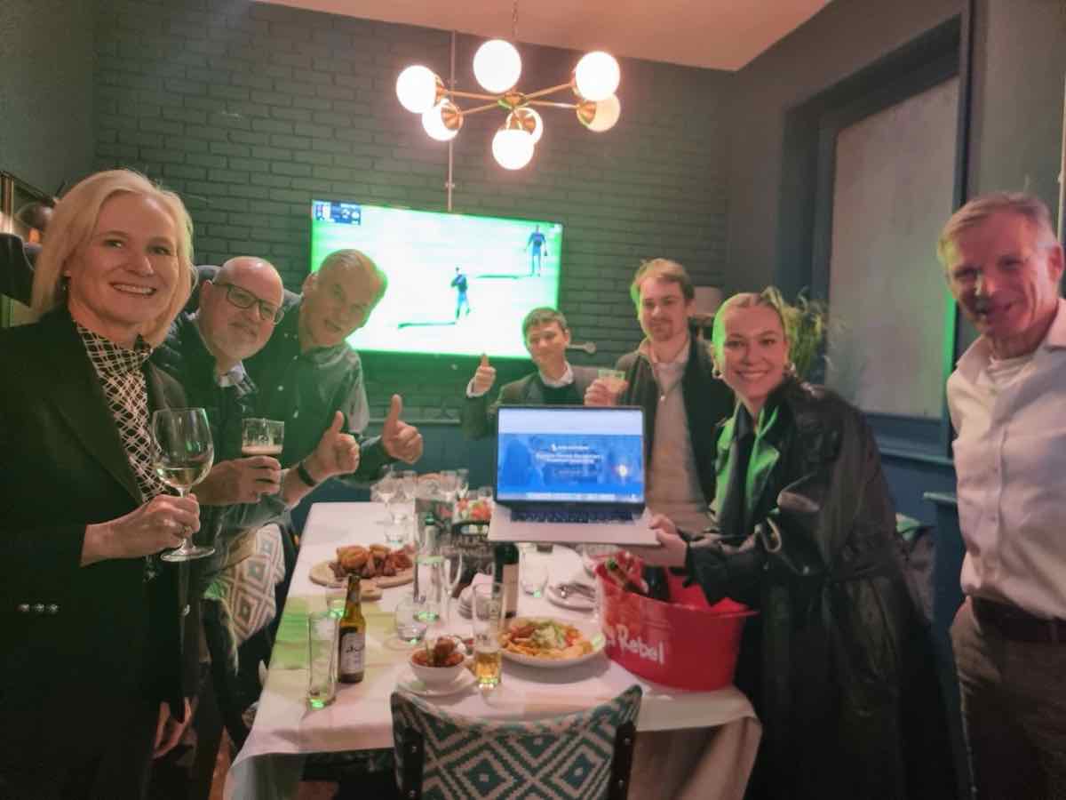 Taylor holding a laptop showing the new Avida International website, celebrating with the team