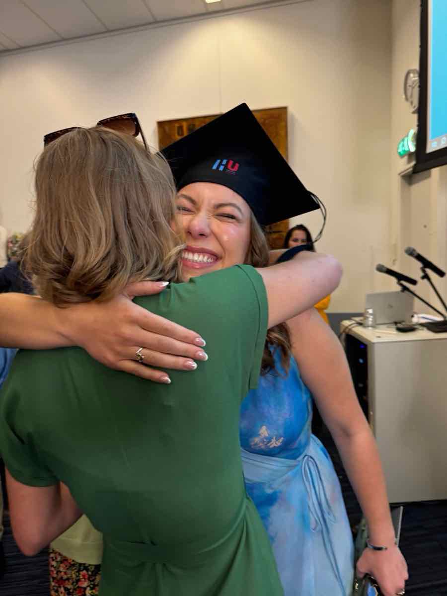 Taylor in a graduation cap sharing a joyful hug after the ceremony