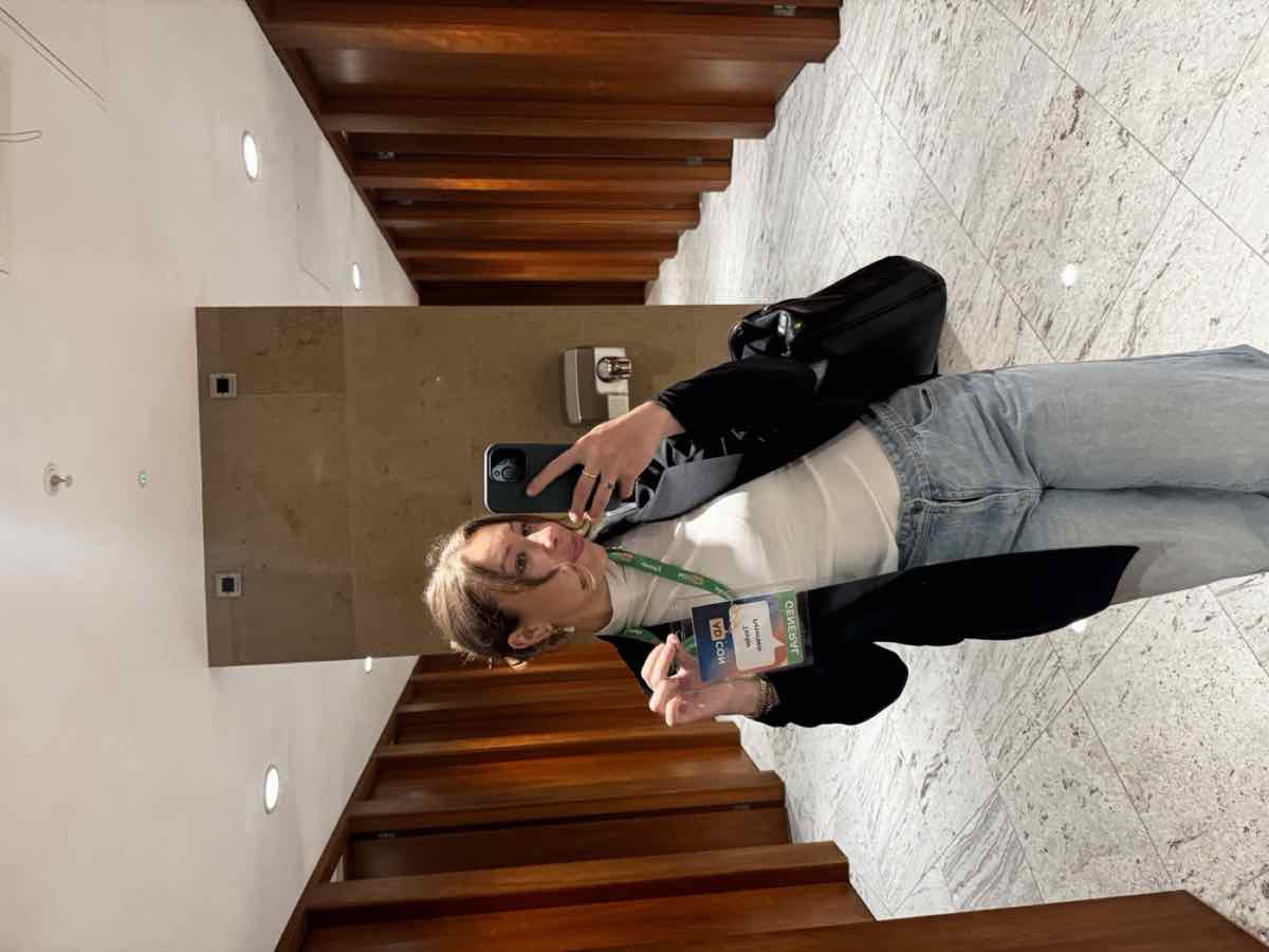 Taylor taking a mirror selfie with a work badge in a London office lobby