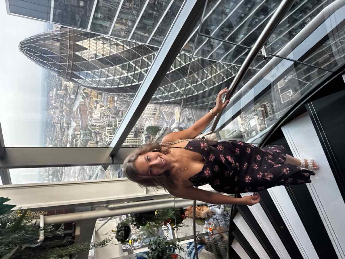 Taylor on a glass staircase with the Gherkin and the London skyline behind