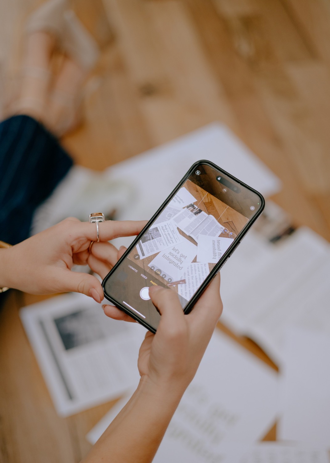 Hands photographing brand materials with a phone
