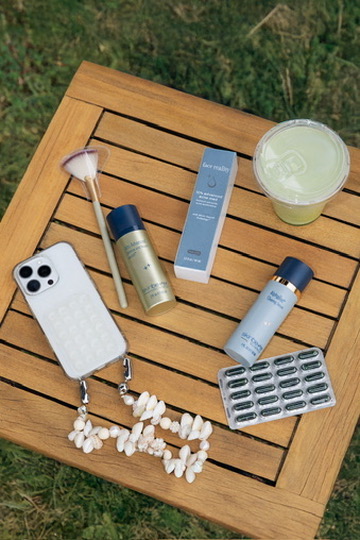 Flat lay of skincare, a phone and a drink on a wooden table