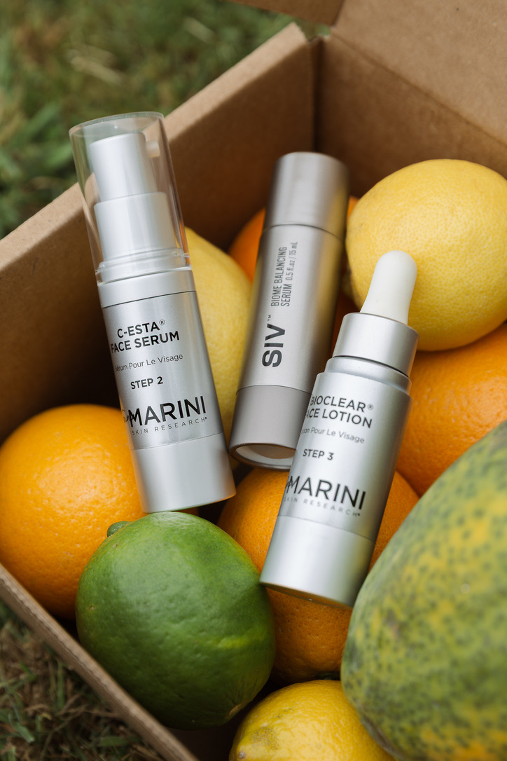 Three skincare serums nestled in a box of citrus and papaya