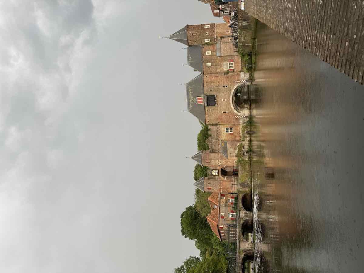 A historic Dutch brick water gate reflected in a canal