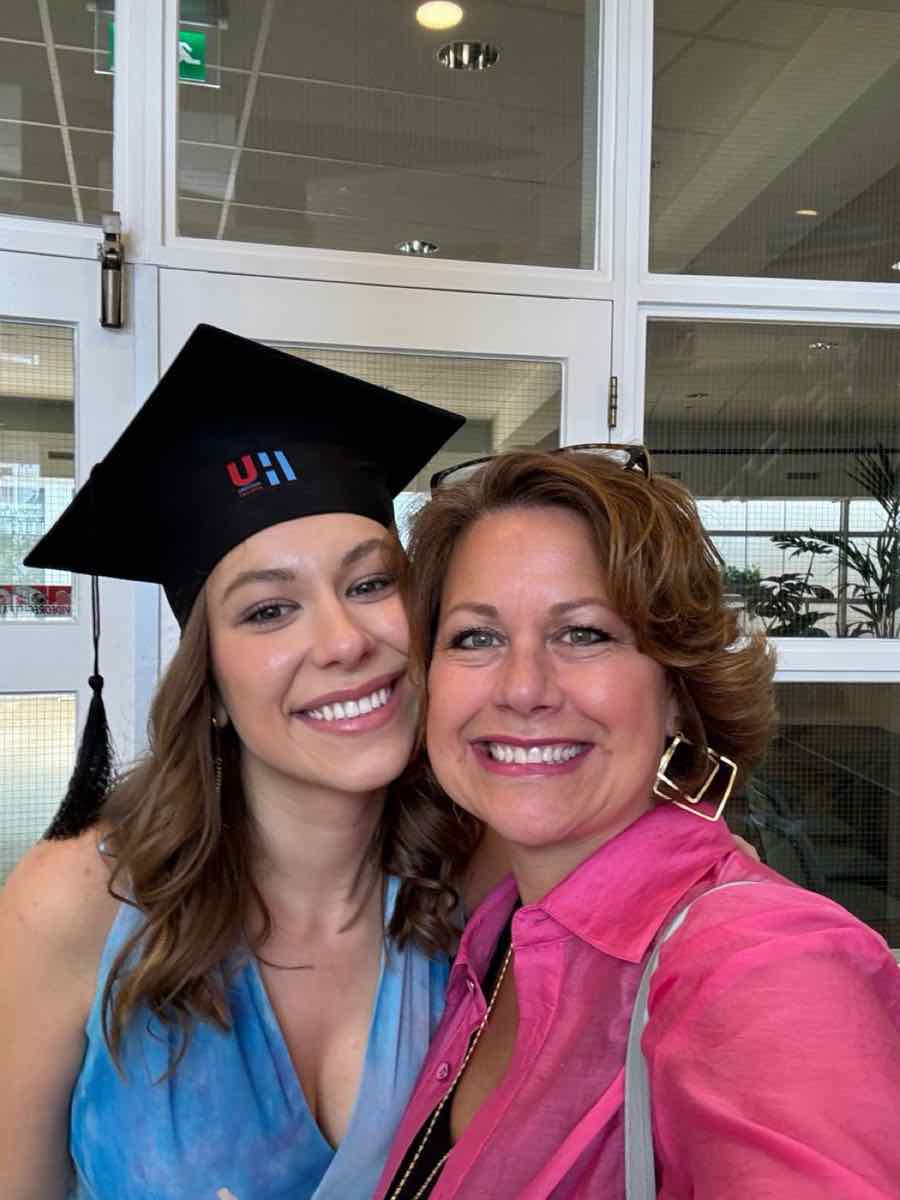 Taylor in an HU graduation cap smiling in a selfie with a loved one