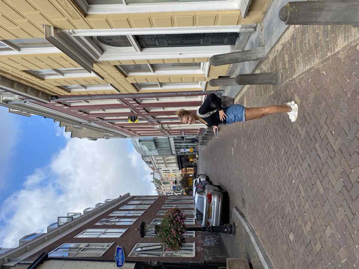 Taylor smiling on a cobbled Utrecht street lined with historic canal houses
